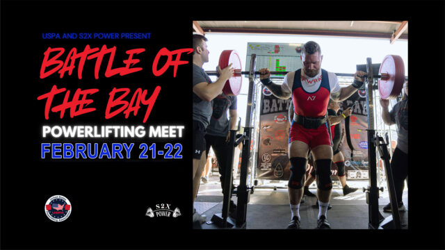 A male powerlifter prepares to squat with a loaded barbell at a powerlifting meet called 