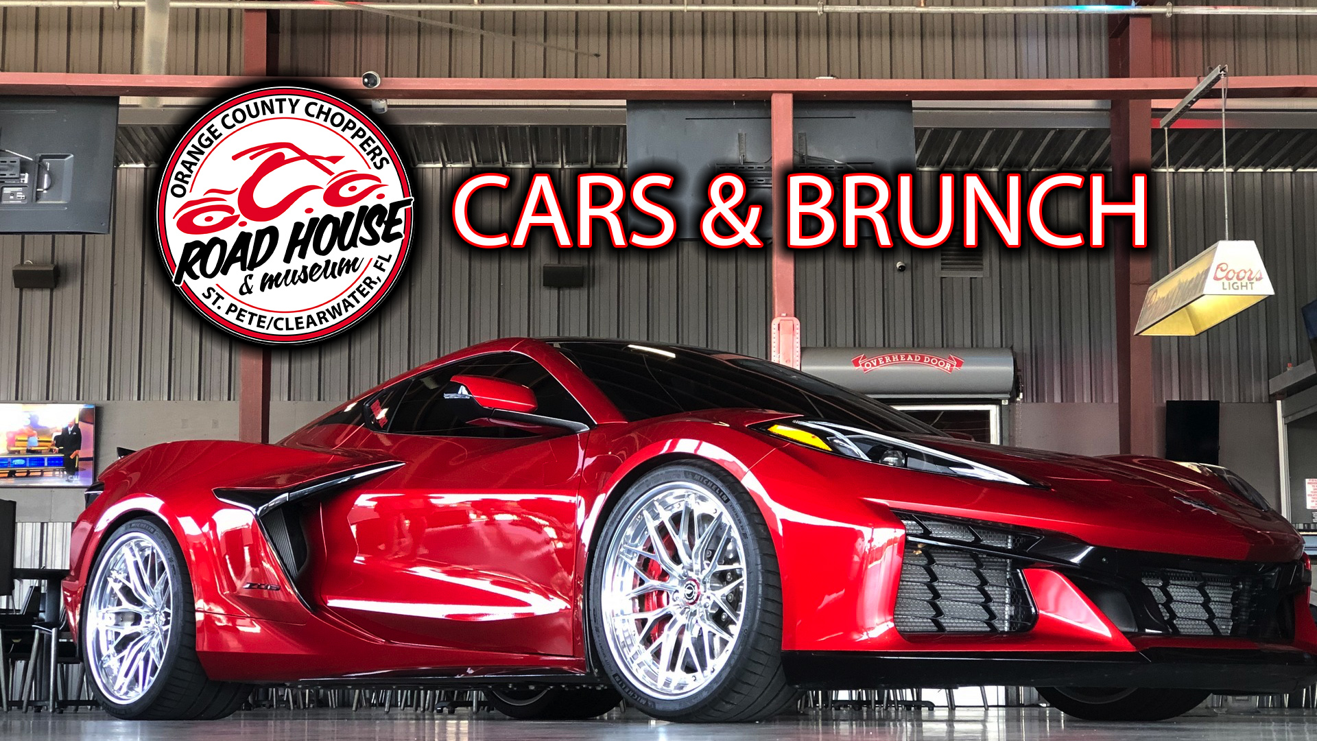 A red sports car is displayed indoors at the Orange County Choppers Road House with a “Cars & Brunch” event sign above.