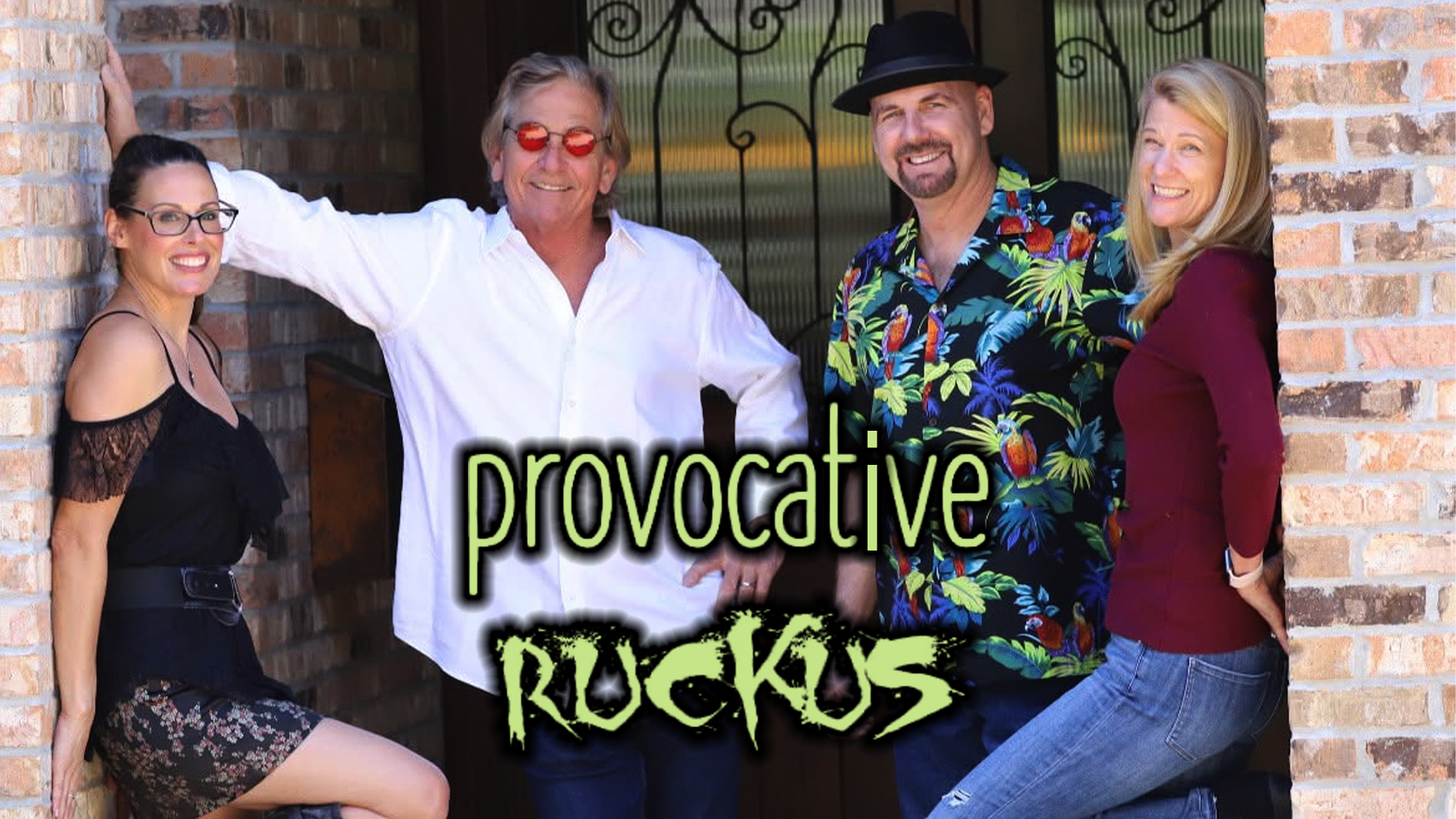 Four adults pose casually outside a brick building with the words 